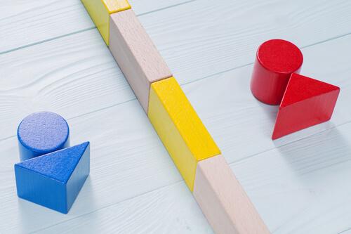 Eine blaue und rote Holzfigur, die durch Bauklötze getrennt sind.