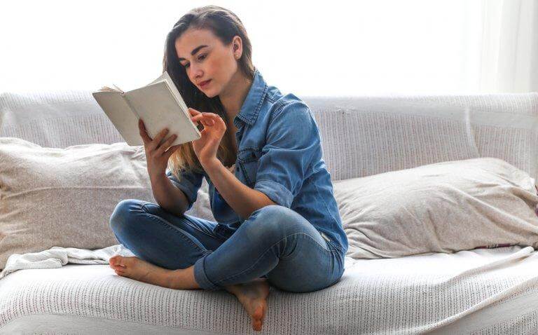 Frau liest ein Buch auf ihrer Couch