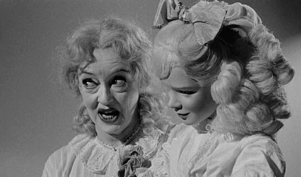 Filmszene aus Baby Jane, die Bette Davis mit einer Puppe zeigt