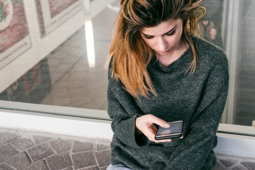 Traurige Frau schaut auf ihr Handy - Die Diktatur des "Gefällt mir" bringt Mängel im Selbstwertgefühl mit sich.