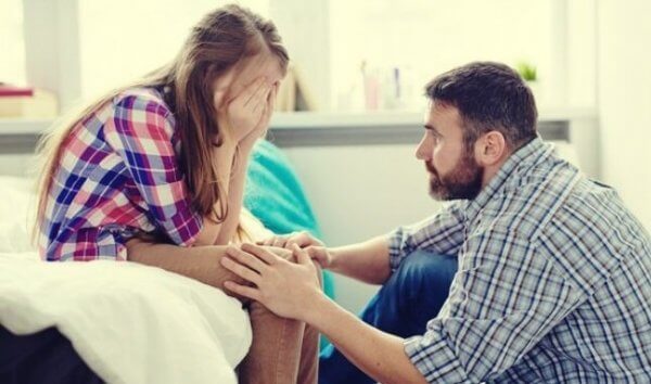 Ein junger Vater spricht mit seiner verzweifelten Tochter und versucht, sie zu trösten.