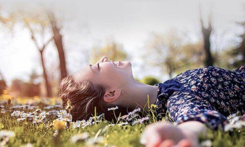 In der Natur auf der grünen Wiese liegende junge Frau