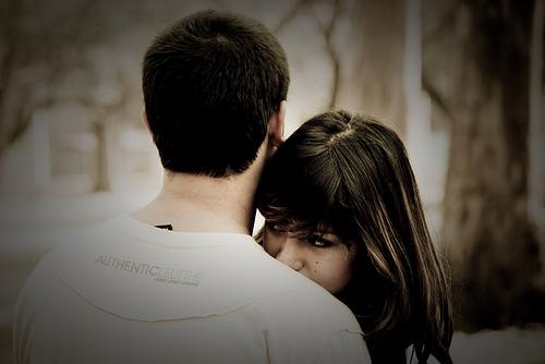 Eine junge Frau lehnt sich an die Schultern ihres Partners an.