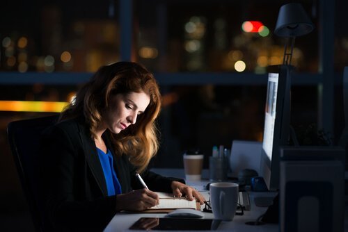 Eine Frau sitzt abends noch im Büro und macht Überstunden. 