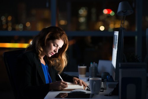 Eine Frau sitzt abends noch im Büro und macht Überstunden.