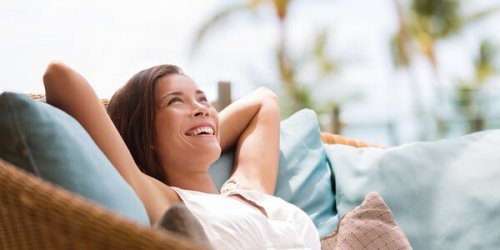 Eine Frau sitzt entspannt in einem Sessel und lacht.