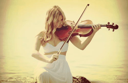 Eine Frau spielt am Meer Geige. 