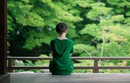 Frau auf der Terrasse schaut ins Grüne