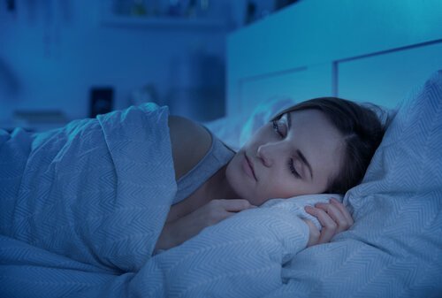Eine Frau liegt bei gedimmtem Licht im Bett.