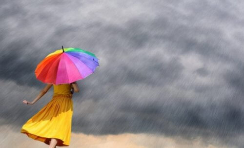 Eine Frau steht mit einem bunten Regenschirm im Regen.