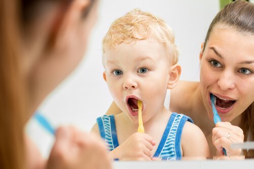 Eine Mutter und ein Kind stehen vor einem Spiegel und putzen sich die Zähne. 