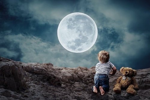 Ein Kleinkind mit Teddy betrachtet den Vollmond.