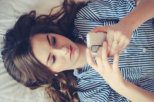 Ein Mädchen liegt auf ihrem Bett, während sie mit ihren Freunden textet. 