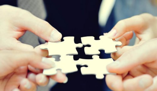 Vier Menschen halten Puzzelteile aneinander.