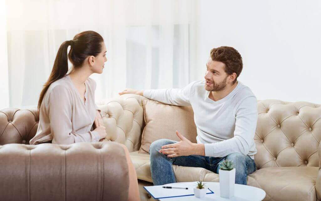 Ein Paar sitzt auf der Couch und spricht miteinander