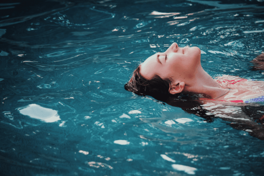 Frau treibt mit einem Lächeln im Gesicht auf der Wasseroberfläche