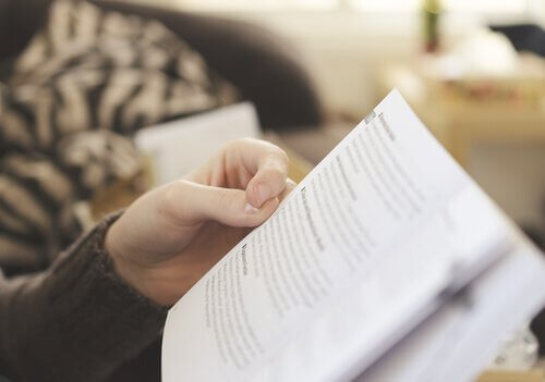 Eine Person sitzt auf einer Couch und liest ein Buch. 