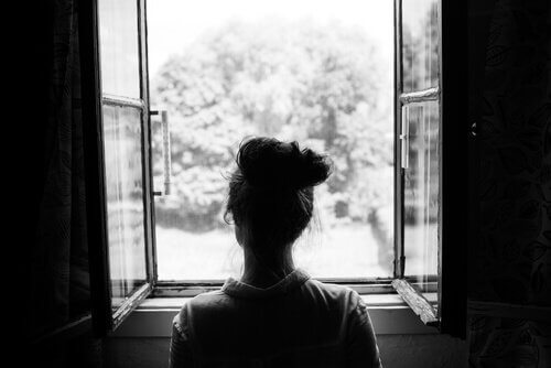 Eine pessimistische Frau schaut durch ein geöffnetes Fenster.
