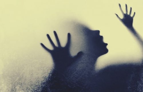 Ein Schatten einer Frau, die Hilfe sucht, hinter einem Milchglas