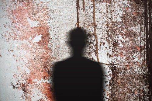 Schatten eines Mannes, der auf eine mit rot gesprengte Wand fällt