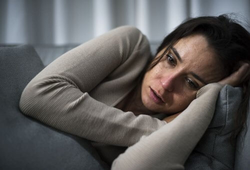 Eine traurige Frau liegt auf ihrer Couch.