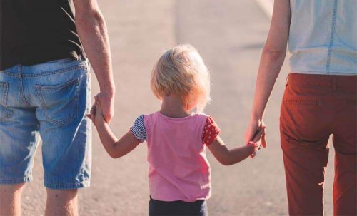 Eltern halten ihr Kind an den Händen.
