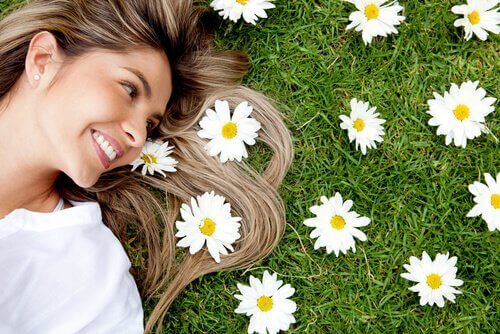 Frau, die fröhlich ist und lächelt, liegt auf einer Wiese voller Blumen