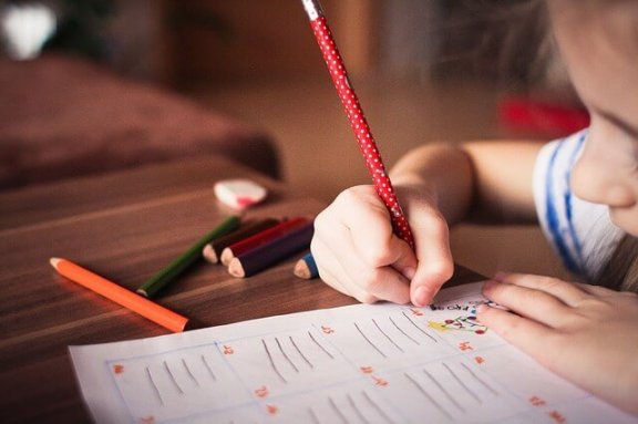 Ein Mädchen schreibt mit einem Buntstift. 