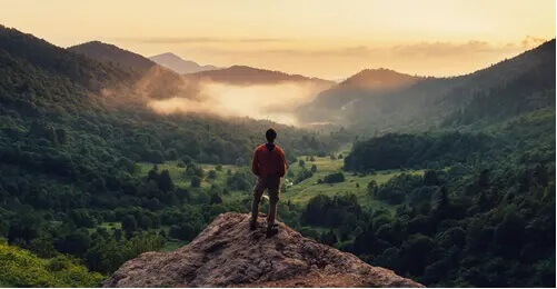 Mann steht auf einem Berg