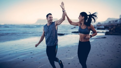 Ein Mann und eine Frau joggen entspannt an einem Strand und haben Spaß. 