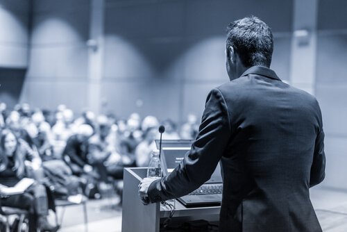 Ein Professor steht am Rednerpult, während er seine Vorlesung hält.