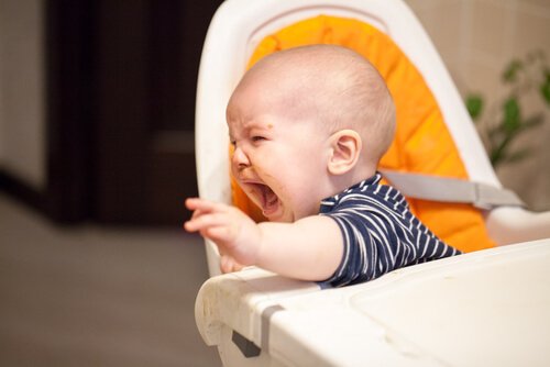 Ein schreiendes Baby sitzt in seinem Hochstuhl. 