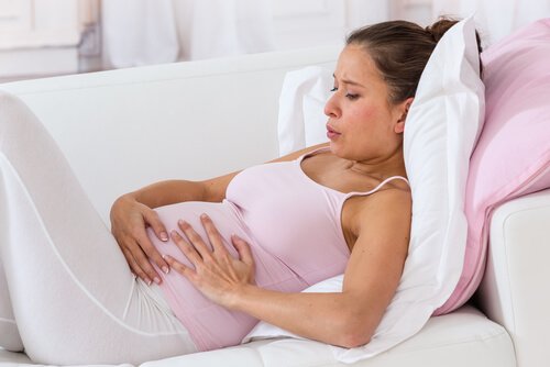 Eine schwangere Frau übt Atemtechniken auf der Couch.