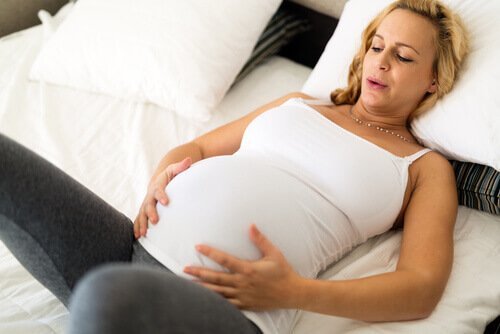 Eine hochschwangere Frau macht Atemübungen.