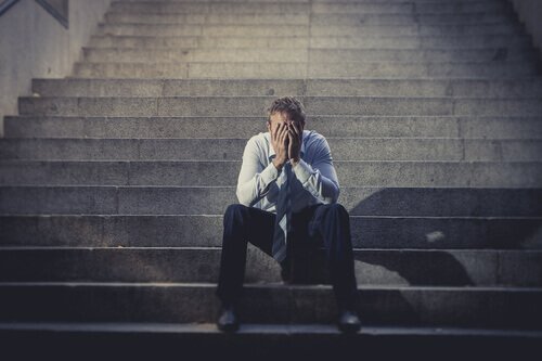 Ein Mann sitzt niedergeschlagen auf einer Treppe. 