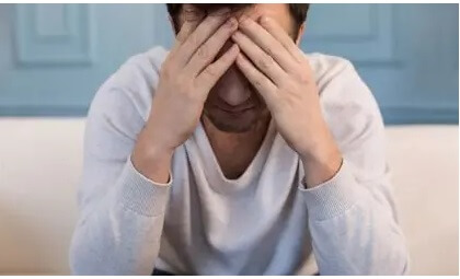 Mann stützt seinen Kopf erschöpft auf seine Hände