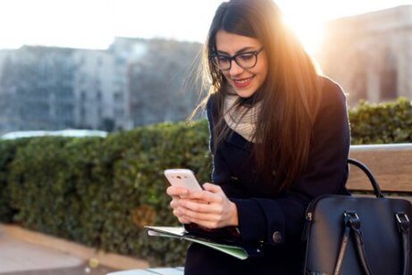Frau auf einer Parkbank bedient ihr Handy