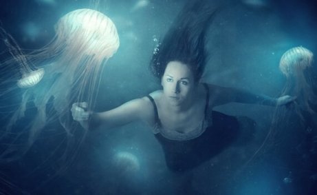 Frau schwimmt unter Wasser mit Quallen