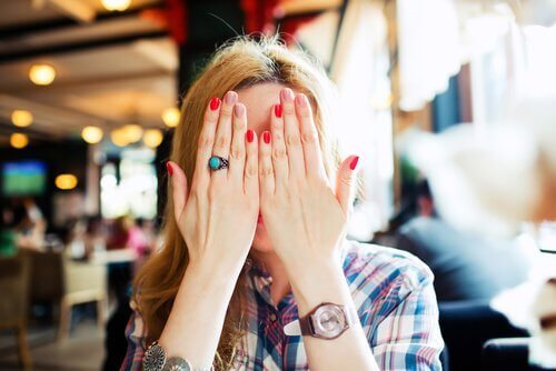 Eine junge Frau versteckt ihr Gesicht hinter ihren Händen.