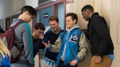 Jungen auf dem Schulhof lachen, während sie auf ein Handy schauen
