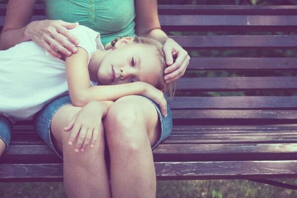 Trauriges Mädchen mit Kopf auf den Beinen seiner Mutter