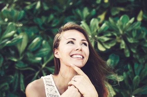 Eine lachende Frau denkt nach und wartet auf Inspiration.