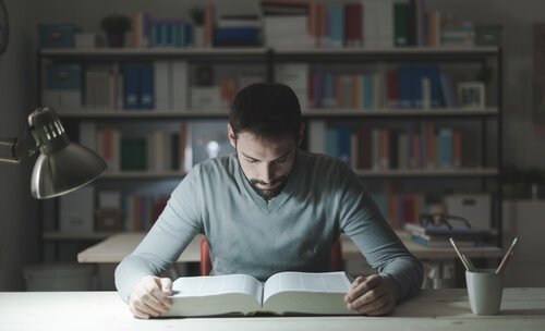 Ein Mann lernt mit einem dicken Buch.