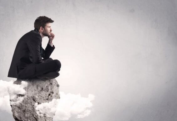 Denkender Mann sitzt auf einem Fels