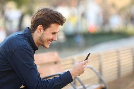 Ein Mann lacht, während er sein Handy bedient.