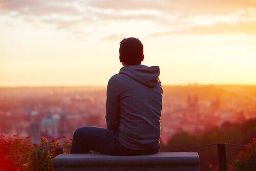 Ein introvertierte Mensch sitzt allein auf einem Dach und beobachtet den Sonnenuntergang.