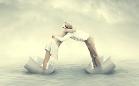 Mann und Frau umarmen sich, während sie in kleinen Papierbooten auf dem Meer schwimmen