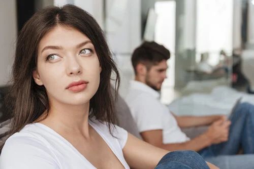 Nachdenkliche Frau neben ihrem Partner, der liest
