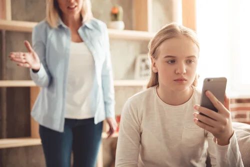 Mutter diskutiert mit ihrer Tochter, die auf ein Telefon schaut