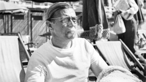 Jean-Paul Sartre sitzt in einem Strandkorb.